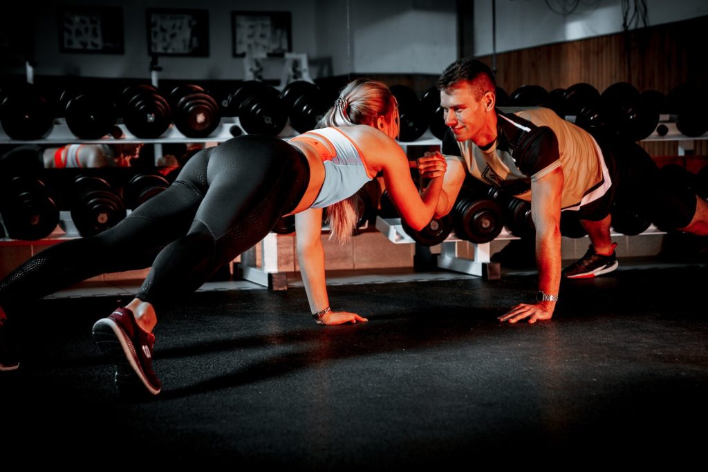 A Couple Holding their Hands while Doing Push-Ups