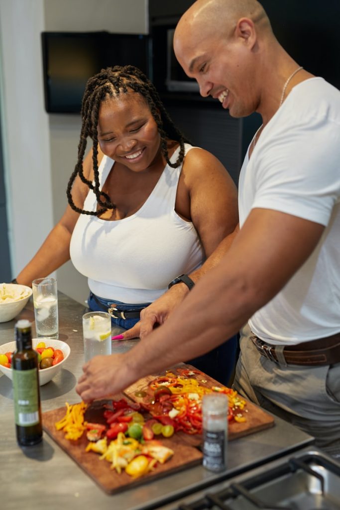 a man and a woman are cutting up a pizza